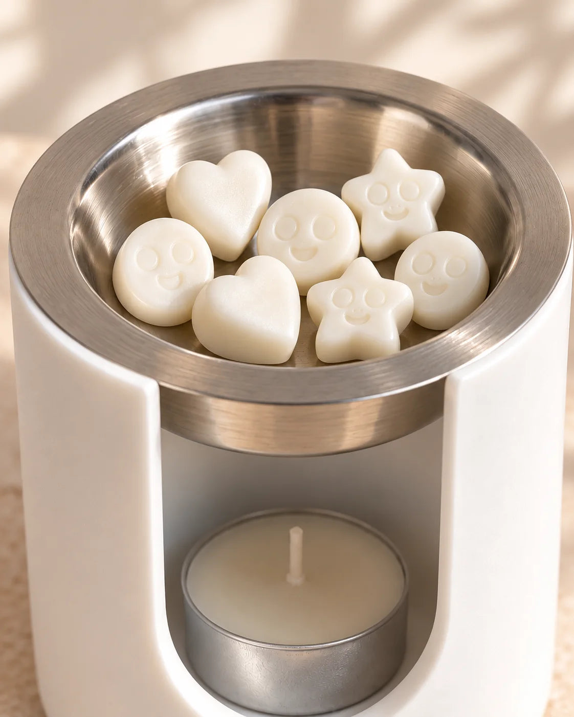 Detalle del bol metálico extraíble del quemador ZAEVA con wax melts en forma de corazón, estrella y carita